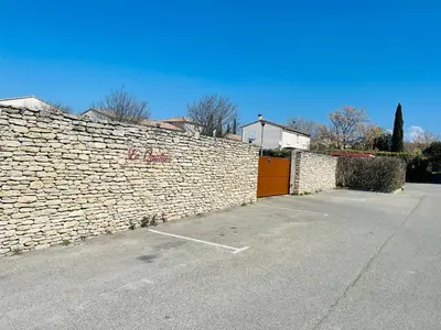a stone wall with a parking lot next to it at Apartment with beautiful terrace in LʼIsle-sur-la-Sorgue