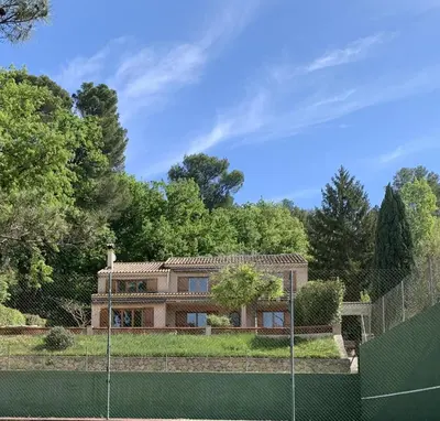 a house behind a fence with a tennis court at Villa CHATEAU SAINTE BARBE in Loriol-du-Comtat