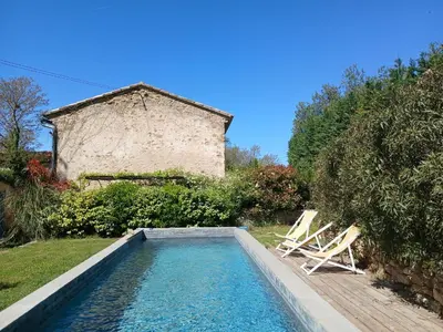 a swimming pool with two chairs and a house at Studio indépendant avec piscine proche Lourmarin in Lourmarin
