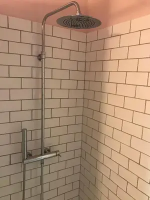 a shower in a bathroom with white tiles at Studio indépendant avec piscine proche Lourmarin in Lourmarin