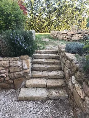 a stone retaining wall and stairs in a garden at Studio indépendant avec piscine proche Lourmarin in Lourmarin