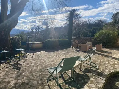 a group of chairs sitting on a stone patio at Bastide entièrement rénovée au coeur de Goult in Goult