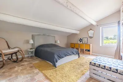 a bedroom with a bed and a chair and a window at Mas provençal, entre vignes et oliviers in Lambesc