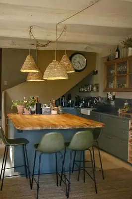 a kitchen with a bar with chairs and a clock at Mas provençal, entre vignes et oliviers in Lambesc