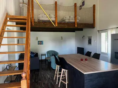 a room with a loft bed and a table with chairs at Gîte The Butterfly - 1 bedroom and mezzanine in Monteux