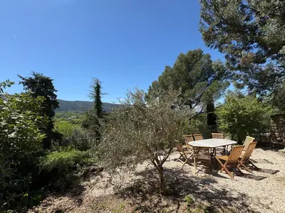 a picnic table and chairs on a hill with trees at Les 2 voûtes - Mas provençal pour 10 personnes in Oppède