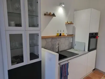 a kitchen with white cabinets and a sink at La maison du quai in LʼIsle-sur-la-Sorgue