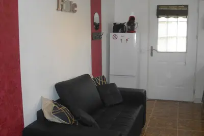 a living room with a black couch and a refrigerator at Lou mas li Pitchoun 