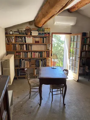 a dining room with a table and chairs and books at La Maison Rose I Maison de village familiale in Lagnes