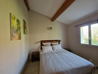 a bedroom with a bed with two pillows and a window at L'Oustalet des Vignes in Saint-Saturnin-les-Apt