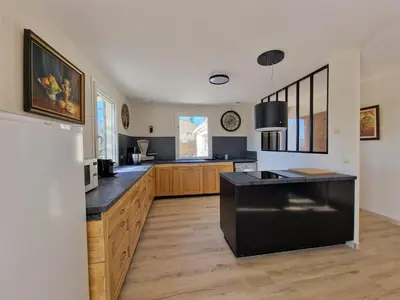 a kitchen with a black island and wooden cabinets at L'Oustalet des Vignes in Saint-Saturnin-les-Apt