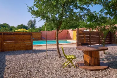 a wooden table and a chair next to a tree at Maison provençale avec jardin in Velleron