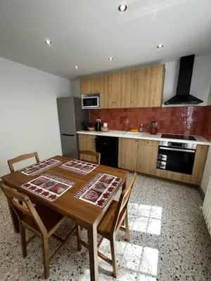 a kitchen with a wooden table with chairs and a stove at Charmant appartement rénové, à 15 mn d'Avignon et de son festival in Entraigues-sur-la-Sorgue