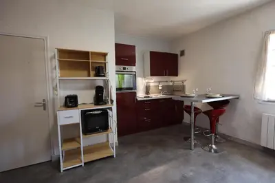 a small kitchen with a table and a counter top at Studio cozy au coeur du village - Wifi - Netflix in Monteux