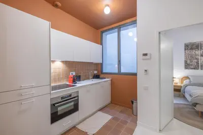 a kitchen with white cabinets and a sink and a bed at Appartement Belle Lettre 5 in Aix-en-Provence