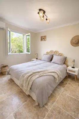 a bedroom with a large bed and a window at Maison en pierre avec piscine chauffée, jacuzzi et vue sur Gordes in Gordes