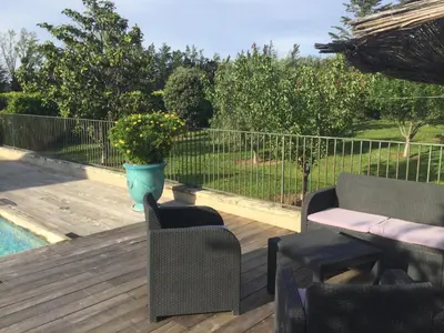 a deck with chairs and a table and a pot of flowers at 1 chambre 1 cuisine & salle d'eau privées avec piscine et jacuzzi in Eyragues