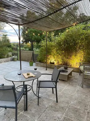 a patio with a table and chairs and an umbrella at Le gîte de Cambuisson in Velleron