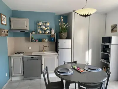 a kitchen with a table and chairs and a kitchen with blue walls at Le gîte de Cambuisson in Velleron