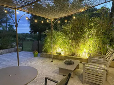 a patio with tables and chairs under a pergola with lights at Le gîte de Cambuisson in Velleron