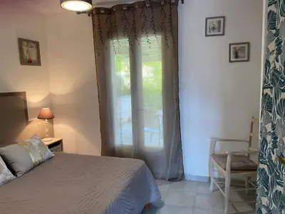 a bedroom with a bed and a window and a chair at Le gîte de Cambuisson in Velleron