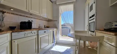 a kitchen with white cabinets and a table and a window at Le Belvédère, Air Conditioning, Freepark 6p in Aix-en-Provence