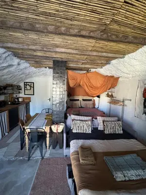 a bedroom with two beds and a table in a room at CaBaNa 52 La Suite troglodyte Proche Lourmarin in Cadenet