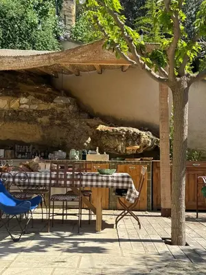a table and chairs in a patio with a stone wall at CaBaNa 52 La Suite troglodyte Proche Lourmarin in Cadenet