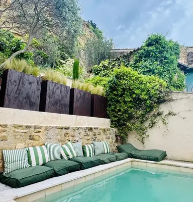 a pool with pillows sitting next to a retaining wall at CaBaNa 52 La Suite troglodyte Proche Lourmarin in Cadenet