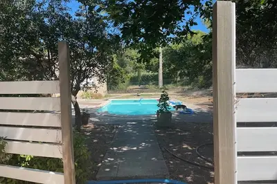 a fence next to a swimming pool in a yard at Maison confortable à Velleron de 50 m² avec piscine in Velleron