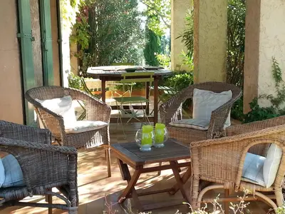 a patio with wicker chairs and a table with glasses on it at Maison de charme en Luberon à proximité de Lourmarin piscine privée et grand jardin in Puyvert