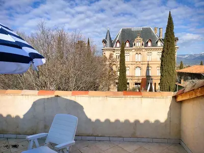 a chair and an umbrella in front of a building at GitesLuberon 5 in Charleval