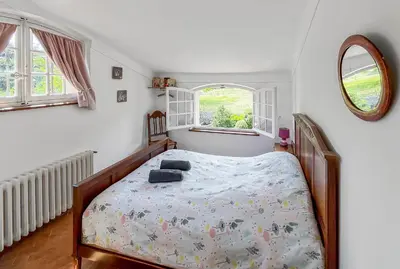 a bedroom with a bed and two windows at Mon coeur de Provence in Banon
