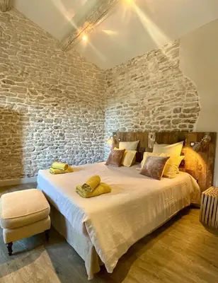 a bedroom with a large bed with a stone wall at Le Mas de Cabrières in Cabrières-dʼAvignon