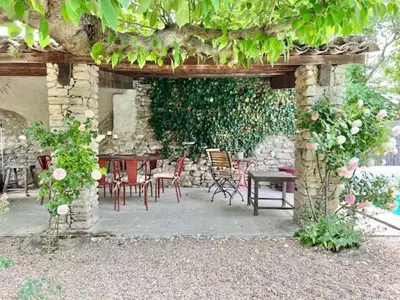 a patio with a table and chairs under a stone wall at Le Mas de Cabrières in Cabrières-dʼAvignon