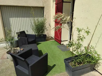 a small garden with grass and chairs and plants at Chambre indépendante avec SDB privative in Avignon