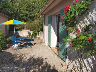 a table and chairs with an umbrella next to a building at Studio Les Alizés du Luberon in Pertuis
