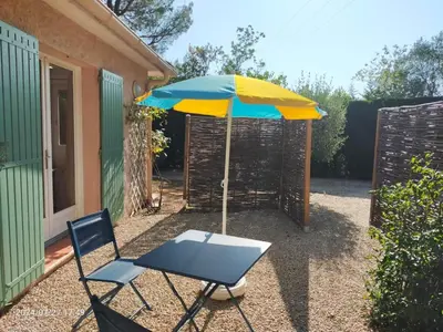 a table and a chair and an umbrella at Studio Les Alizés du Luberon in Pertuis
