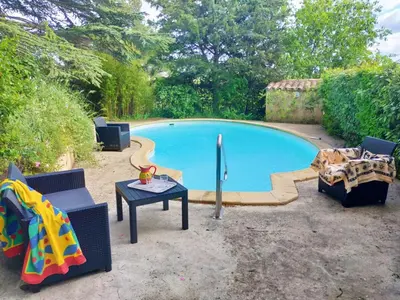 a pool with two chairs and a table next to it at Studio Les Alizés du Luberon in Pertuis