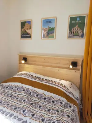 a bedroom with a bed with three pictures on the wall at Studio Les Alizés du Luberon in Pertuis