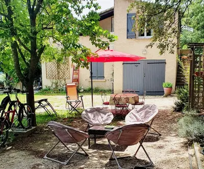 a patio with chairs and a table and a red umbrella at Les Marronniers Charmant petit appartement a La Tour d'Aigues Vaucluse in La Tour-dʼAigues