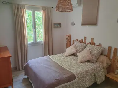 a bedroom with a bed with pillows and a window at Les Marronniers Charmant petit appartement a La Tour d'Aigues Vaucluse in La Tour-dʼAigues