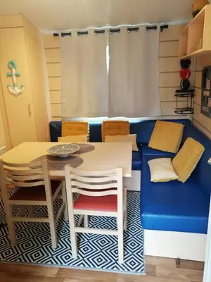 a living room with a blue couch and a table and chairs at mobil home chez ANIK & ALAIN in La Roque-dʼAnthéron