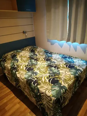 a bed in a room with a blanket on it at mobil home chez ANIK & ALAIN in La Roque-dʼAnthéron