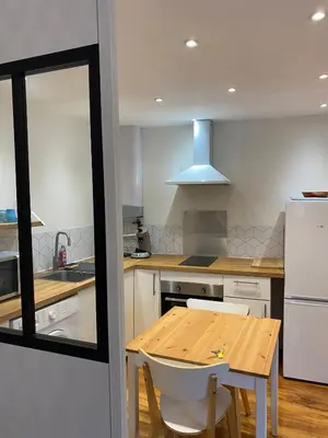 a kitchen with a wooden table and white appliances at Studio Cosy in Pélissanne