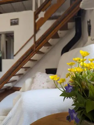 a bed and a table with a vase of yellow flowers at La Bergerie de Lorette - Au Cœur du Luberon in Bonnieux