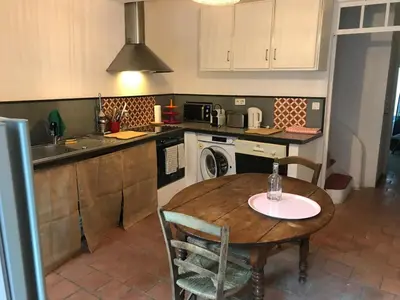 a kitchen with a table and a sink and a stove at Lubéron Grde Maison de village avec terrasse 4 chambres doubles in Saint-Martin-de-Castillon