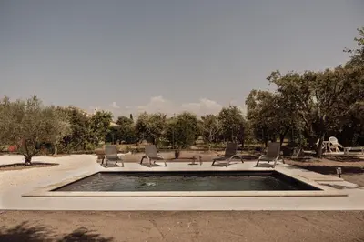 a pool of water with chairs in a park at La Villa Des Garrigues in Mazan