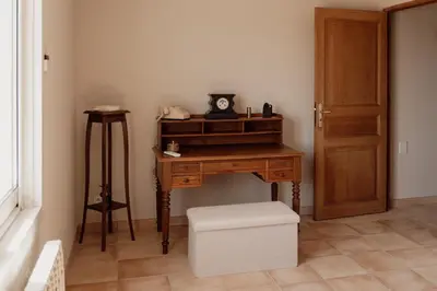 a room with a desk with a clock and a stool at La Villa Des Garrigues in Mazan