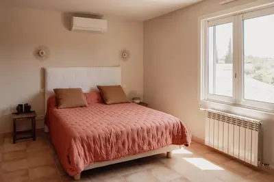 a bedroom with a bed and a large window at La Villa Des Garrigues in Mazan